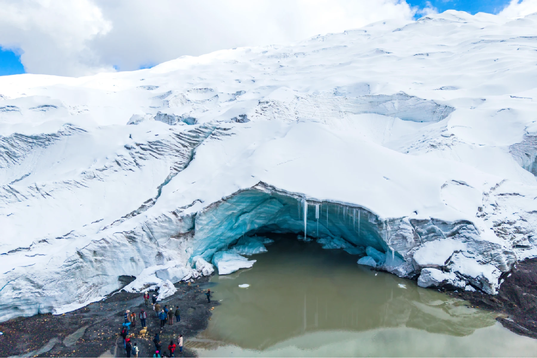 A group of explorers near Qelqaya glacier in Cuzco, surrounded by stunning ice formations and a bright blue sky.